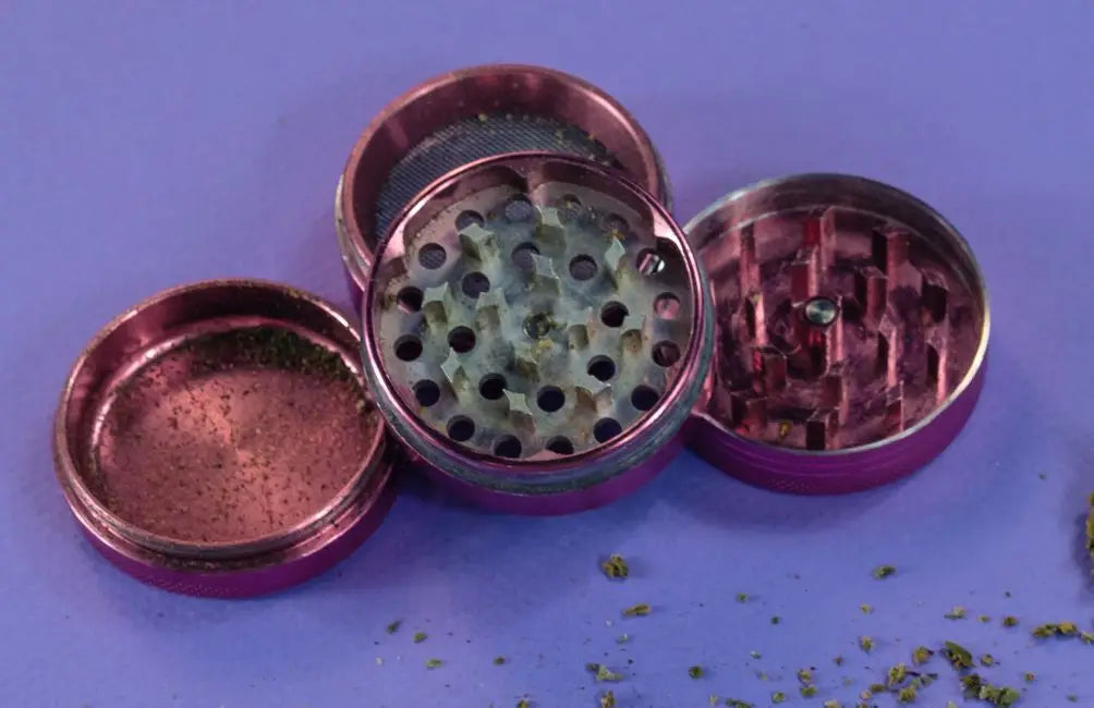 Gebräuchlicher metallisch-pink Grinder mit Sieb und Zähnen aus dem Grinder Guide