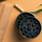 Schwarzer Metall-Grinder mit diamantförmigen Zähnen und Loch